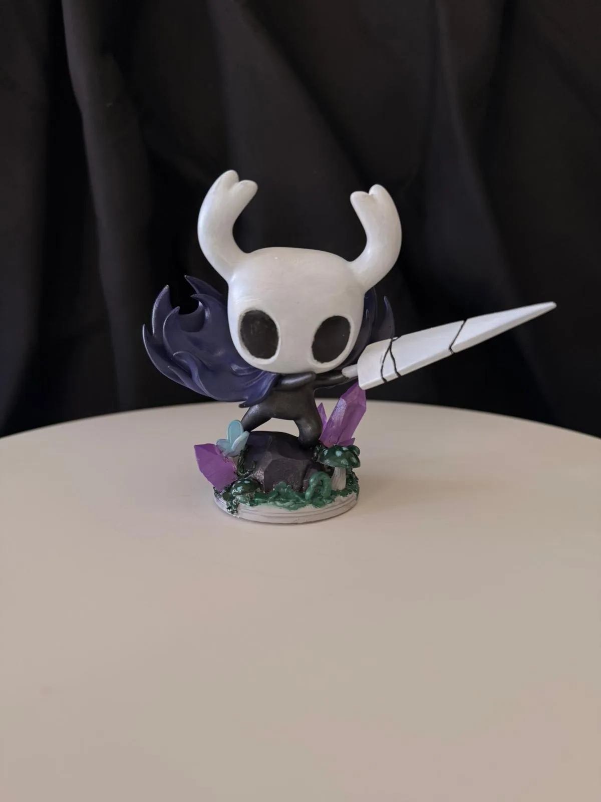 Mor kristalli taban üzerinde Hollow Knight figürü