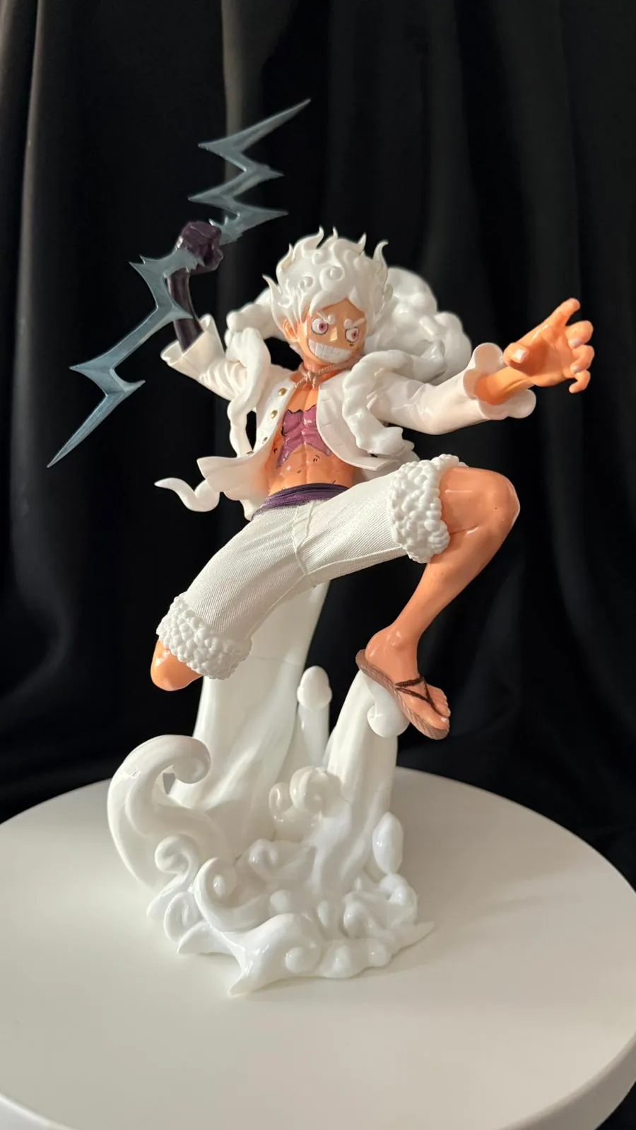 Bulut ve şimşek efektli taban üzerinde Luffy Gear 5 figürü