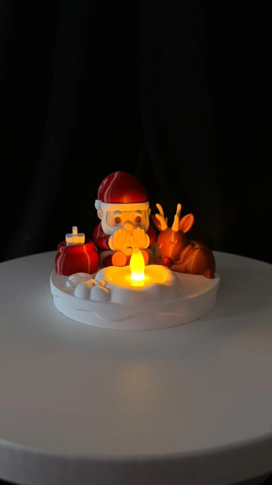 Işıklı kamp ateşinin yanında oturan Noel Baba ve ren geyiği dekoru
